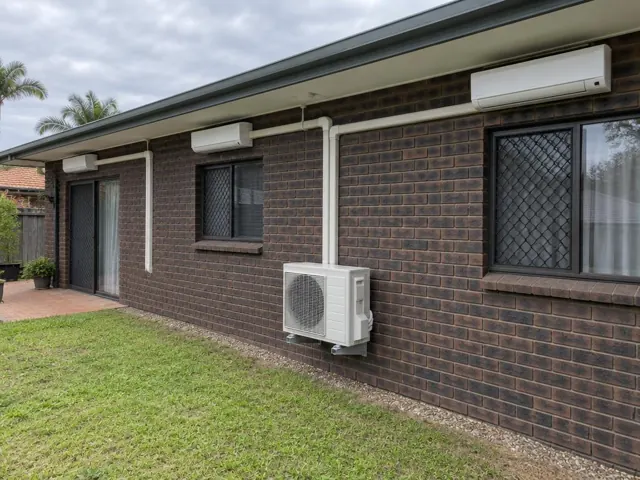 Three wall-mounted split units with white pipe covers and one outdoor condenser on a brick house in Benowa