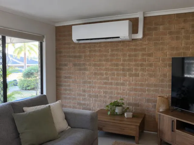 Wall-mounted split system above a brick feature wall in a living room in Carrara